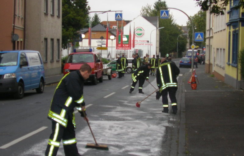Feuerwehrleute streuen die Fahrbahn ab
