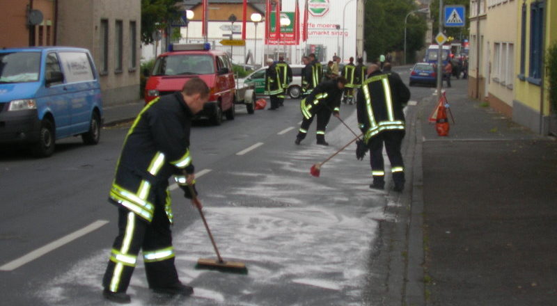 Feuerwehrleute streuen die Fahrbahn ab